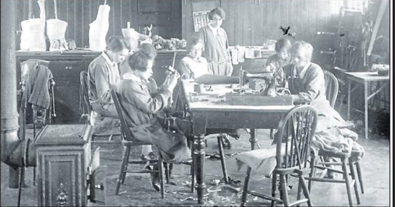 Black and white photo in a splint shop at an orthopaedic Hospital. A group of women are group seated around a table working.
